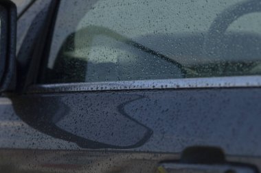 Eğri yansıma ve yağmur boncukları gösteren detaylı ıslak araba paneli, serin tonlu minimum şehir kompozisyonu