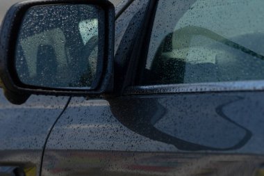 Soyut çizgileri ve parlak damlacıkları olan ıslak araba gövdesi, karamsar altında boya ve panel kıvrımları yakın plan