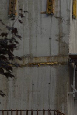 Aşınma ve çapaları gösteren engebeli beton duvar paslanmış beton çizgiler ve görünür çapa noktaları olan eskimiş beton duvarlar, sarı aşınma çizgileri ve çıkıntılı delikler.