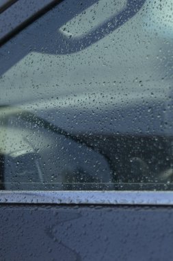 Yağmurla lekelenmiş araba penceresi yakın çekimde direksiyon yansımasını, ıslak yüzey, karamsar ışık, iç mekan