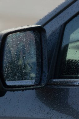 Yan ayna bulanık şehir koltuğunu yağmur damlalarının arasından yansıtıyor, direksiyon ve pencere çerçevesinin iç kısmı...,