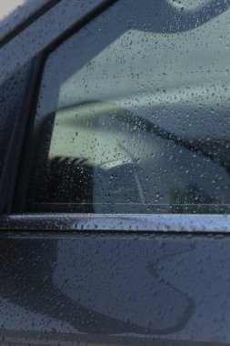 ıslak araba penceresi kısmi direksiyon ve iç siluetleri gösteriyor, sürücü perspektifi park ederken