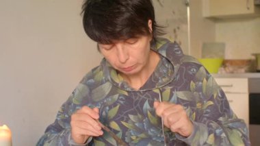 Kadın mutfak tezgahında tat reaksiyonunu kaydediyor. Kaşıkla ve kapüşonlu kapüşonluyla el ve yüz hareketlerini ifade ediyor.