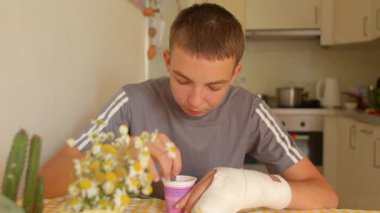 Mutfak masasında kolları dökülmüş yoğurt yiyen gençler, kaşıkla karıştırılmış bardaklar, papatyalar ve ön planda kaktüsler.,