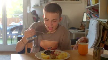 Mutfak masasında portakal suyu, kaşık ısırıkları, rahat duruş ve yumuşak bir sabah.