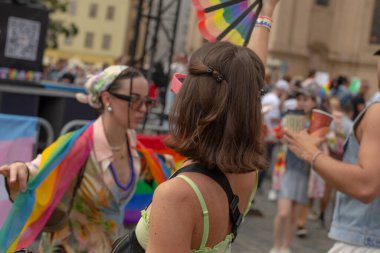 Gökkuşağı fanı ile dans eden beyaz tenli sanatçı, Prag meydanındaki destekçiyle canlı giysiler ve facepaint, hareket CZ, Prag, Na prikope, 2.8.25