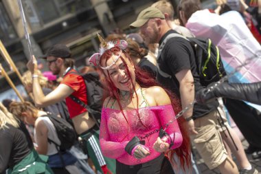 Pembe elbiseli beyaz yürüyüşçü kalabalığın içinden kararlı bir ifadeyle geçiyor, Prag onur yürüyüşüne ve renkli işaretler arasında aktivizm yürüyüşüne katılıyor, CZ, Prag, Na prikope, 2.8.25