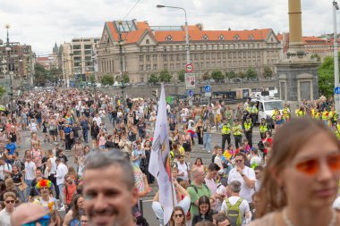 Kalabalık Prag Köprüsü bayrakları sallıyor, tramvay raylarını ve caddeleri dolduran binlerce katılımcı, renkli afişler ve gökkuşağı aksesuarları, neşeli CZ, Prag, Na prikope, 2.8.25