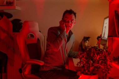 Telefondaki adam, kırmızı ışıkta, ağzı kapatan girişimci kurucunun acil haber almasına şaşırdı. Masa başı kahve fincanı latehour gerilimi, uzaktan haberleşme neon atmosferi.