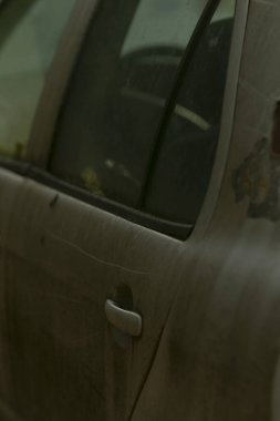 Eski araç detayları, hava kirliliği ve kir belirtileri gösteren araç kirlenmiş ve solmuş boyalı eski otomobil, terk edilmiş araç, pazarın yakınında toprak izleri ve yıpranmış dış cephe sergiliyor.