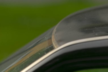 Sabah ışığı ağaçların arasından yansıyor, cam yüzey huzurlu park yansımalarını canlı bir şekilde yakalıyor, ipek gibi pürüzsüz ön cam sakin park manzarasını ve güzel bir sabah aydınlatmasını yansıtıyor.