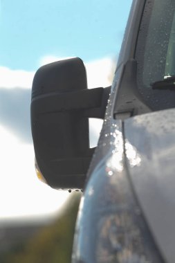 Yüzey atmosferik koşulları açıkça gösteriyor, yansıtıcı yüzey yağmurdan sonra hava detaylarını gösteriyor, aracın üzerindeki yansıtıcı ayna şiddetli yağış sonrasında havanın temizlendiğini gösteriyor