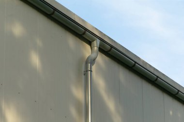 Zarif bina silueti, basit kentsel mimari sahnesi, kıvrımlı drenaj borusu ve sessiz arka planı olan sakin dış görünüş, pürüzsüz eklem ve yumuşak gökyüzü tonuyla modern minimalist bina.