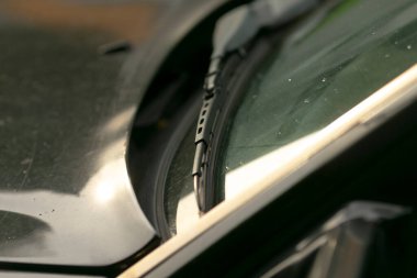 Islak yüzeyde yansıyan şehir manzarası, şehir sokaklarının yansımaları ve parlak araba yüzeyinde yağan yağmur, nemli çizgiler ve şehir manzarası, yağmurlu havalarda parlayan aracın dış yüzeyine canlı bir şekilde yansıyor.