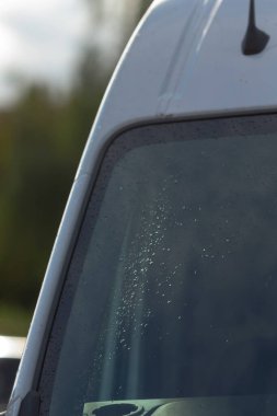 Yağmurlu barışçıl manzara, cam üzerindeki güneşli yağmur damlaları yağmurlu ön camda parıldayan güneş ışığı manzarası sisli ön camda ışıldayan su boncuklarının huzurlu görüntüsü.