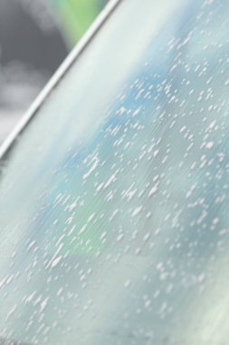 Islak camdaki yansımalar ve gradyanlar, renkli bokeh ile nemli ön camın yakın görüntüsü, atmosferik çekim damlacıkları canlı renk geçişleri ve yansıtıcı dokular yaratan sabun damlacıkları.