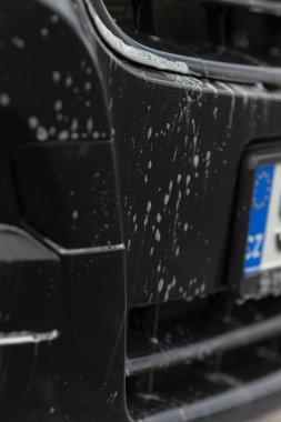 Araç tamponundaki köpüğün detaylı görüntüsü, sabun köpüklü araba tamponunun ve temizlik köpüğünün detaylı görüntüsü, yıkama işlemi sırasında araba tamponunda köpük ve su gösteren ayrıntılı sahne