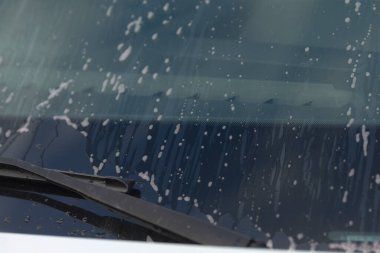 Yağmurlu pencere sahnesi, yağmur damlaları ve araba ön camındaki yansımalar hareket eden sileceklerle camlardaki yağmur izlerini, aktif silecekleri ve yağmur damlalarının yansımalarını gösteren sahne.