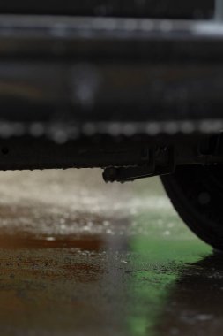 Gölgeli tekerlek ve su damlacıkları, gölgeli tekerleğin altındaki yansıtıcı beton ve damlayan su, alttaki nemli aracın düşük açılı görüntüsü ve beton yüzeyde su damlaları ve gölgeler.