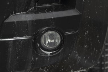 Servis sırasında sis lambasının yakın görüntüsü, rutubetli ve kirli sis lambasını gösteren ayrıntılı fotoğraf, bakım sırasında sabun kalıntısı ile arabanın sis ışığını yakalayan kapsamlı görüntü