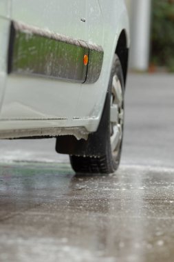 Islak yollarda yol alan şehir aracı, yağmurun ve spreyin ortasında kaygan kentsel yollarda giden kargo aracı, yağmurlu şehir yollarında lastik izleri ve su püskürtücü ile çalışan teslimat minibüsleri.