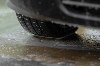 Lastik izlerinin detaylı görünümü, lastik yüzeyinde su boncukları ve lastik desenlerini gösteren yakın perspektif, su damlacıklarını yakalayan yüksek çözünürlüklü makrolar ve lastik lastik izi alanında desenli kauçuk.