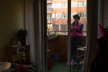 Balkondaki işçiler dışarıyı gözetliyor, karanlık ufuk çizgisi ve birkaç blok ötede loş bir iç mekan, perde ve parti şapkası, parlak yelek giymiş siluetli figür ve vardiya sırasında duraklamalar, huysuz şehir sakinleri.