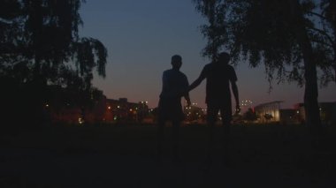 Şehir ışıkları parladıkça şehir siluetleri egzersizleri, akşam ışığında parlayan şehir siluetiyle ısınan erkekler, parlayan şehir silueti ve kentsel çevre altında arkadaşlarla sosyal akşam egzersizleri