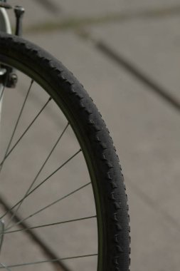 Kaldırımın kenarındaki bisiklet lastiği profili, betona karşı desenli lastik silueti, taşıma ve tasarım için ideal minimalist kentsel hareketlilik bileşimi.