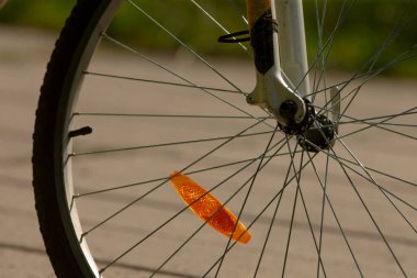 Bisiklet jantının ve yansıtıcının yakın çekimi, güvenlik özelliklerine sahip bisiklet tekerleğinin detaylı görüntüsü, kaldırımlı yolda bisiklet tekerleği bileşenleri ve güvenlik unsurlarını gösteren yukarıdan görüntü