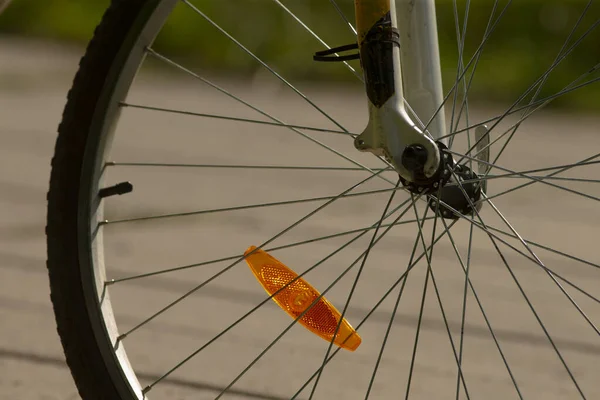 Bisiklet jantının ve yansıtıcının yakın çekimi, güvenlik özelliklerine sahip bisiklet tekerleğinin detaylı görüntüsü, kaldırımlı yolda bisiklet tekerleği bileşenleri ve güvenlik unsurlarını gösteren yukarıdan görüntü