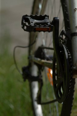 Döngüsel bileşen detaylarının kapatılması, bisiklet pedalı ve zincir sisteminin ayrıntılı görünümü, bisiklet mekanizmasının ve eğitim veya sürat oturumunu gösteren çevrenin vurgulanması