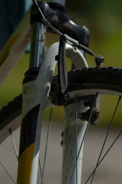 Eski bisiklet ön montajının yakından incelenmesi, eski bisiklet süspansiyonunun ayrıntılı çekimi, boya parçaları ve kir, yıpranmış ön çatal ve klasik bisiklet freninin fotoğraflanması.