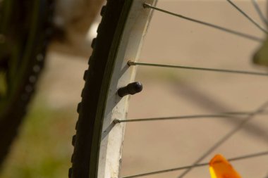 Uygun enflasyon için valf ve jant denetimi, hazırlıklar sırasında kapak ve jant kapağının yakın görüntüsü, yolculuktan önce enflasyon kontrolüne işaret eden ayrıntılı lastik kapakçığı atışı ve kenar ölçümü