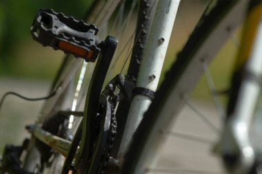 Bisiklet bileşenlerini ayarlayan tamirci, gres ve kirle bisiklet sürüş yağmurunu gösteren atölye ortamı, bisiklet zincirinin ayrıntılı görüntüsü ve mekanik akort ekipmanıyla raydan çıkarıcı.