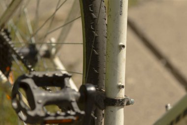 Güneş ışığı bisiklet pedalı ve çerçeve ayrıntıları, çamuru ve iyi kullanılan özellikleri gösteren motosikletin yakın çekimi, bisiklet pedalı ve çerçeve çizimlerinin ayrıntılı görünümü aşınma ve günlük şehir kullanımı