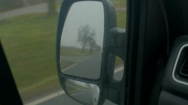 Sakin kırsal manzara, sessiz yeşillik geçiyor, bulutlu bir gün, nemli camda çıplak ağaçları yakalıyor, nemli camlarda yapraksız ağaçları yansıtan huzur dolu kırsal yol.