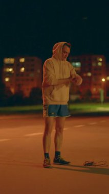 Gece meydanı seansında şınav çeken kendini adamış bir erkek sporcu var. Sıcak ışıklandırma koşulları altında şınav çeken bir adamla akşam yoğun bir çalışma.