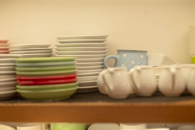 Arka rafta temiz tabak ve bardaklar, restoranın iç depolama alanı temiz çizgileri ve hızlı servis almak için verimli bir yerleşimi olan düzenli pastel ve beyaz bulaşık takımlarını gösteriyor.