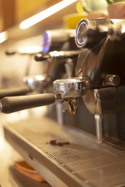 Çoklu grup espresso makinesi iç mekan, servis sırasında barista takımı ritmi, damlatma tepsisinin üzerine dizilmiş birden fazla portafinter, sıcak kafe ışıklarını yansıtan paslanmaz yüzey ve hız