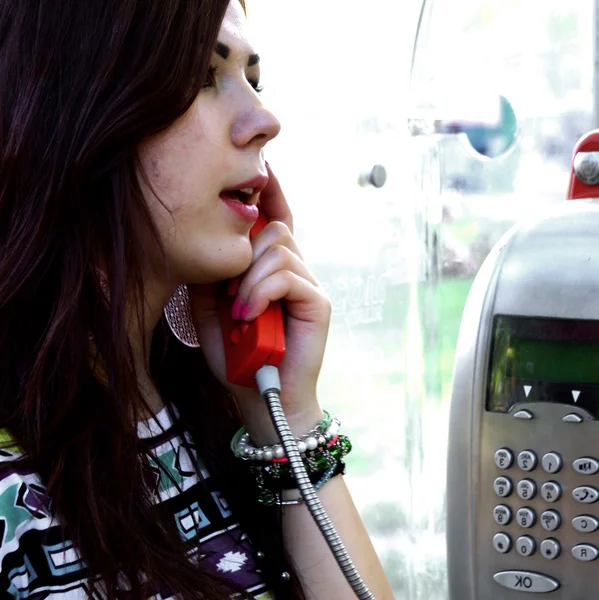 Young woman talking on a pay phone — Stock Photo, Image
