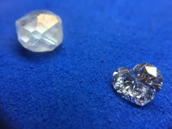 Rough diamond and diamond in the shape of a heart on a blue cloth — Stock Photo, Image