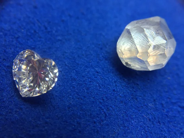 Diamante áspero y diamante en forma de corazón sobre un paño azul — Foto de Stock