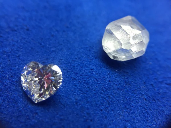 Diamante áspero y diamante en forma de corazón sobre un paño azul — Foto de Stock