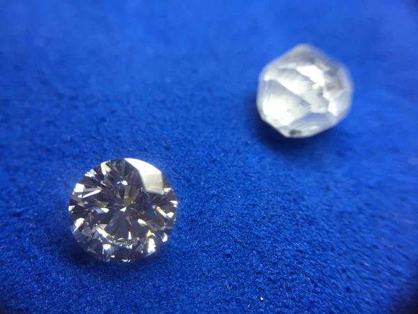 Необработанные алмазы и алмазы круглой формы на голубом фоне — стоковое фото