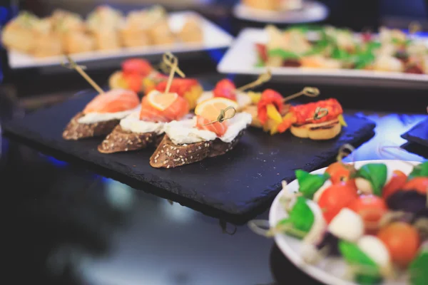 Beautifully decorated catering banquet table with different food snacks and appetizers with sandwich, caviar, fresh fruits on corporate christmas birthday party — Stock Photo, Image