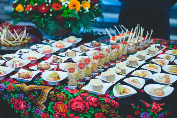 Beautifully decorated catering banquet table with different food snacks and appetizers with sandwich, caviar, fresh fruits on corporate christmas birthday party — Stock Photo, Image