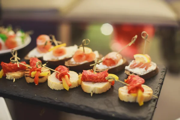 Mesa de banquete de catering lindamente decorada com diferentes lanches e aperitivos de alimentos com sanduíche, caviar, frutas frescas na festa de aniversário de Natal corporativa — Fotografia de Stock