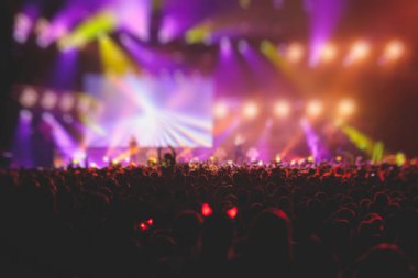 Sahne ışıklarıyla kalabalık bir konser salonu, rock gösterisi performansı, insanların silueti, bir konser festivali sırasında dans pistinde renkli konfeti patlaması.