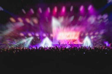 Sahne ışıklarıyla kalabalık bir konser salonu, rock gösterisi performansı, insanların silueti, bir konser festivali sırasında dans pistinde renkli konfeti patlaması.
